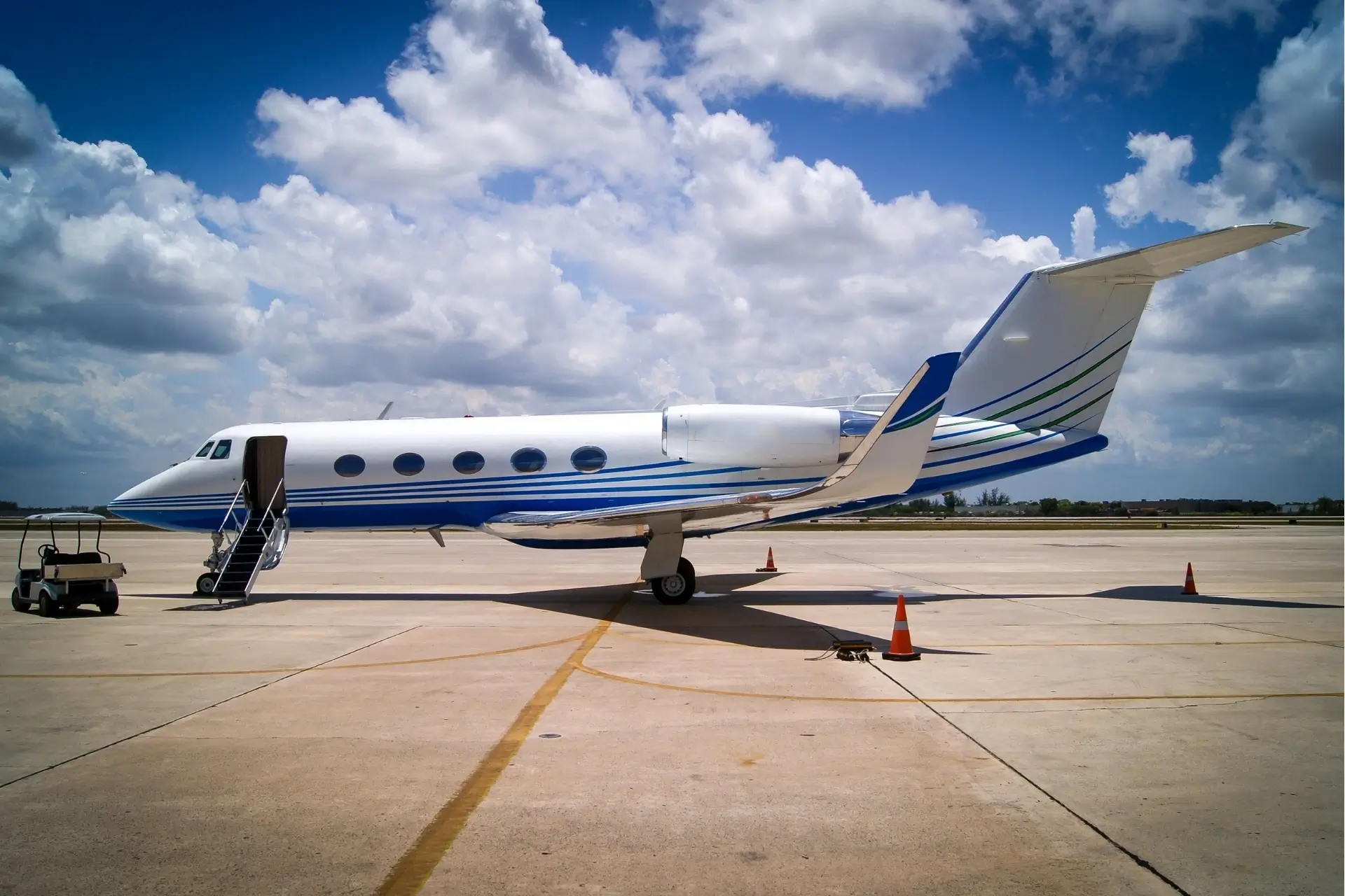 Private jet parked on airport tarmac under clouds